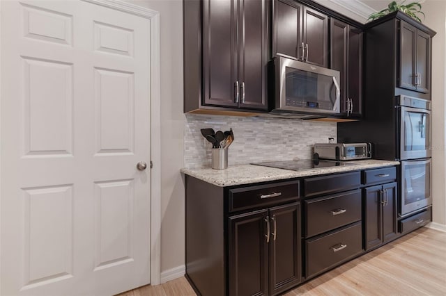 595 American Holly Pl, Oviedo, FL 32765 - kitchen featuring appliances with stainless steel finishes, decorative backsplash, light wood-style flooring, light stone countertops, and baseboards