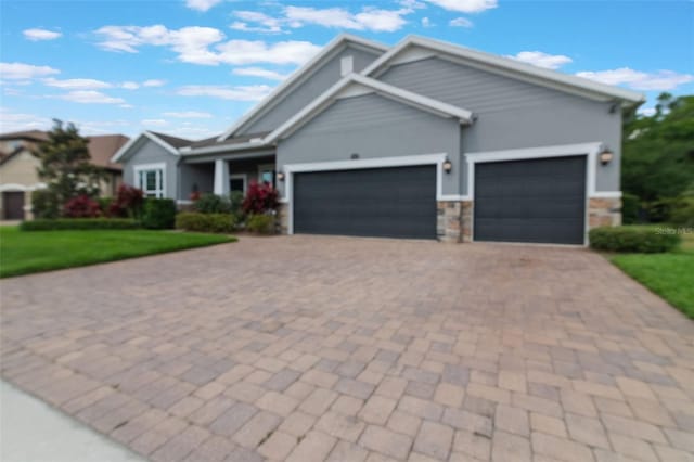 595 American Holly Pl, Oviedo, FL 32765 - view of front of property with an attached garage, decorative driveway, a front lawn, stone siding, and stucco siding