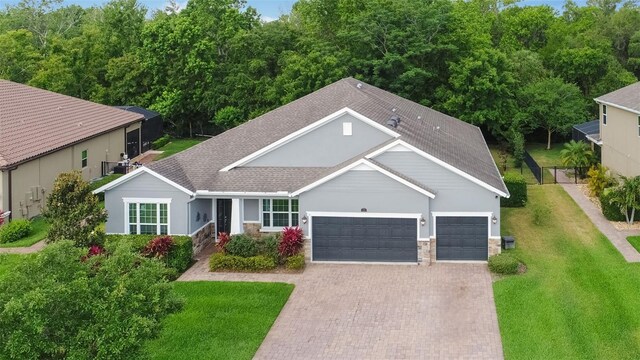 595 American Holly Pl, Oviedo, FL 32765 - single story home with roof with shingles, an attached garage, stone siding, decorative driveway, and a front lawn
