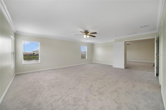 empty room with ornamental molding, ceiling fan, carpet floors, and baseboards