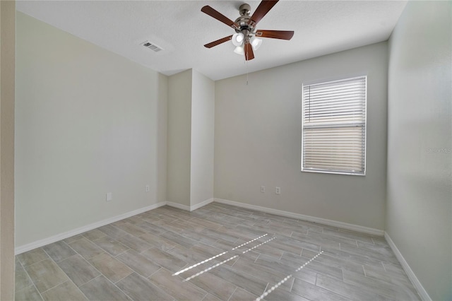 spare room with a ceiling fan and baseboards
