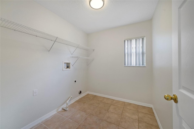 washroom featuring electric dryer hookup, hookup for a washing machine, light tile patterned flooring, and baseboards