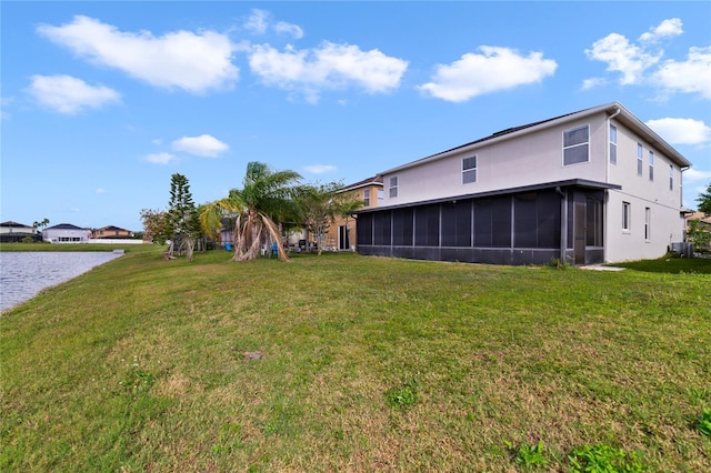 back of property featuring a sunroom, a yard, stucco siding, central AC unit, and a water view