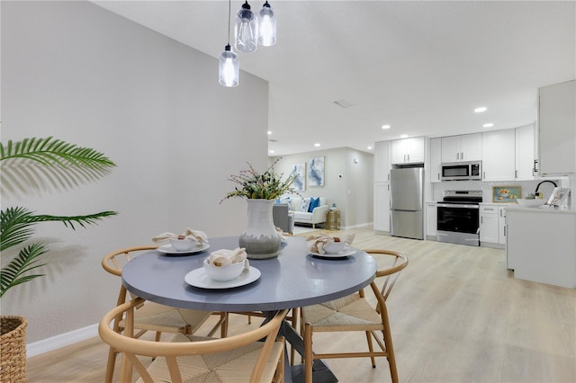 dining space with light wood-style flooring, baseboards, and recessed lighting
