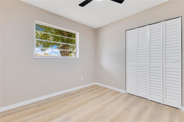 unfurnished bedroom with wood finished floors, baseboards, a closet, and a ceiling fan