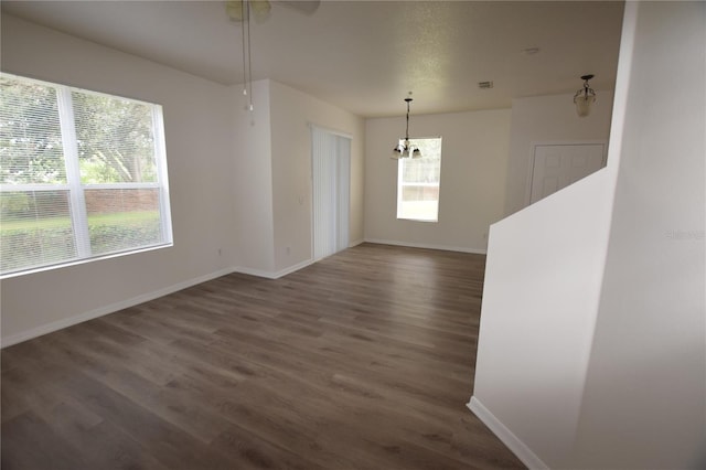 unfurnished dining area with dark wood-style flooring, baseboards, and a chandelier