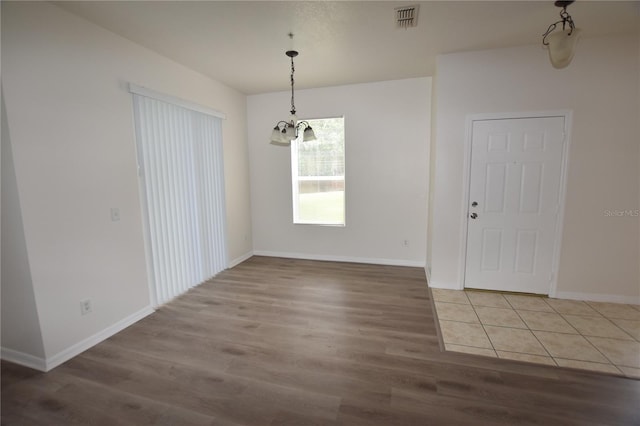 unfurnished dining area with light wood-type flooring, baseboards, and a chandelier