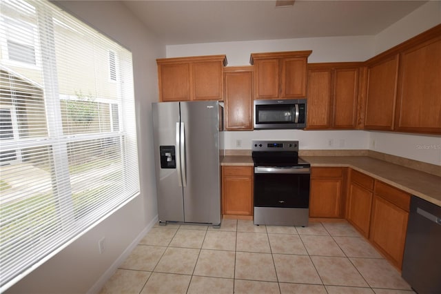 kitchen featuring appliances with stainless steel finishes, light countertops, brown cabinets, and light tile patterned flooring