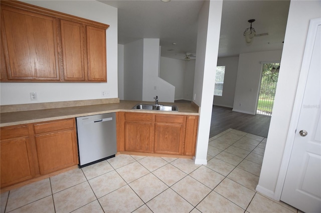 kitchen with stainless steel dishwasher, a sink, brown cabinets, and light tile patterned flooring