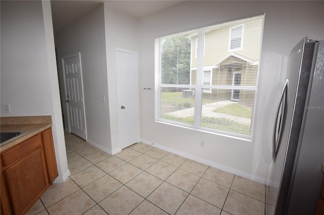 unfurnished dining area with light tile patterned floors and baseboards