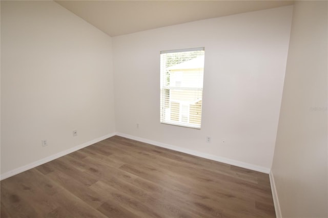 unfurnished room featuring wood finished floors, baseboards, and lofted ceiling