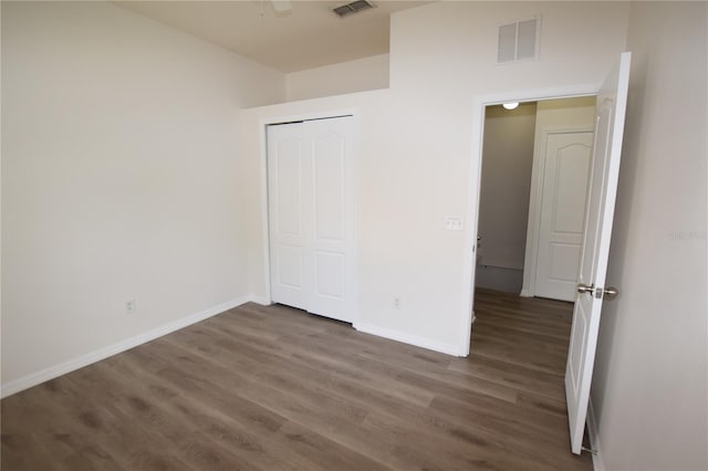 unfurnished bedroom with wood finished floors, baseboards, and a closet