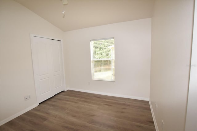 empty room featuring wood finished floors, vaulted ceiling, baseboards, and a ceiling fan