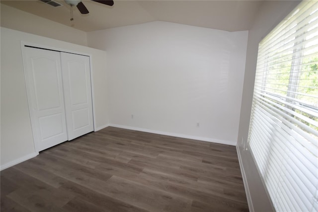 unfurnished bedroom featuring wood finished floors, lofted ceiling, baseboards, a closet, and ceiling fan