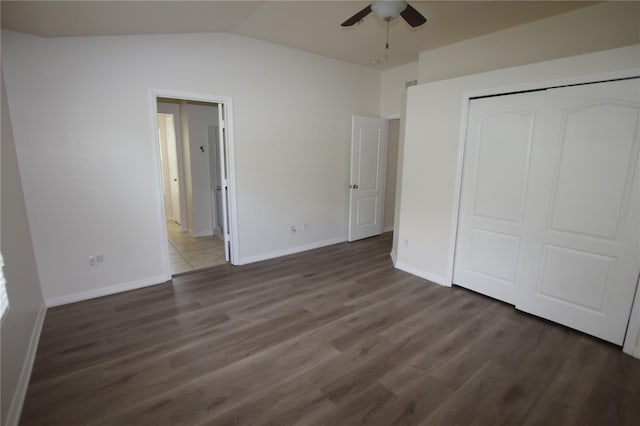 unfurnished bedroom featuring wood finished floors, a closet, baseboards, vaulted ceiling, and a ceiling fan