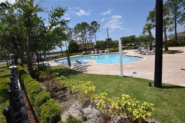 community pool with a patio and a lawn