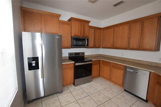15349 Oak Apple Ct, Winter Garden, FL 34787 - kitchen with appliances with stainless steel finishes, brown cabinetry, and light tile patterned flooring