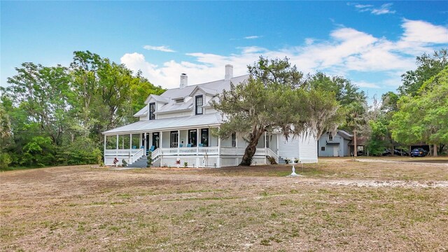 511 E Mirror Lake Dr, Fruitland Park, FL 34731 - view of front of house with covered porch, a chimney, a front lawn, and metal roof