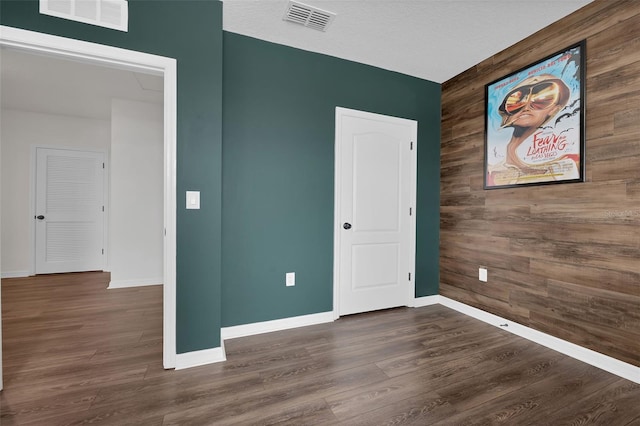 455 Lazio Cir, Debary, FL 32713 - unfurnished bedroom featuring an accent wall, wood walls, baseboards, and dark wood finished floors