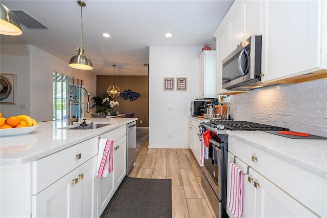 6543 Orange Cream Aly, Winter Garden, FL 34787 - kitchen with appliances with stainless steel finishes, a sink, decorative backsplash, white cabinetry, and wood finish floors