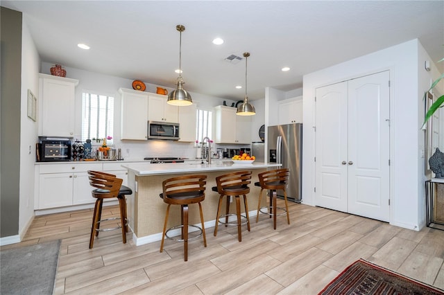 6543 Orange Cream Aly, Winter Garden, FL 34787 - kitchen featuring appliances with stainless steel finishes, healthy amount of natural light, wood finish floors, a breakfast bar, and recessed lighting