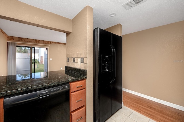 738 Haven Pl, Tarpon Springs, FL 34689 - kitchen with black appliances, light tile patterned floors, dark stone countertops, brown cabinetry, and baseboards