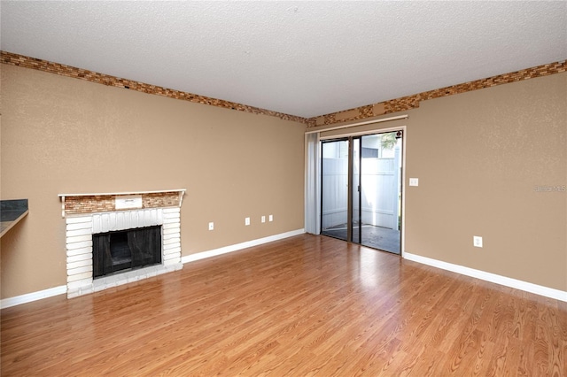 738 Haven Pl, Tarpon Springs, FL 34689 - unfurnished living room featuring light wood-style flooring, a brick fireplace, baseboards, and a textured ceiling