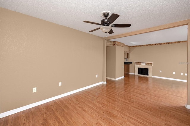 738 Haven Pl, Tarpon Springs, FL 34689 - unfurnished living room with a ceiling fan, light wood-style flooring, baseboards, a fireplace, and a textured ceiling