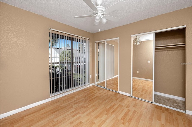 738 Haven Pl, Tarpon Springs, FL 34689 - unfurnished bedroom with two closets, wood finished floors, a textured ceiling, baseboards, and a ceiling fan