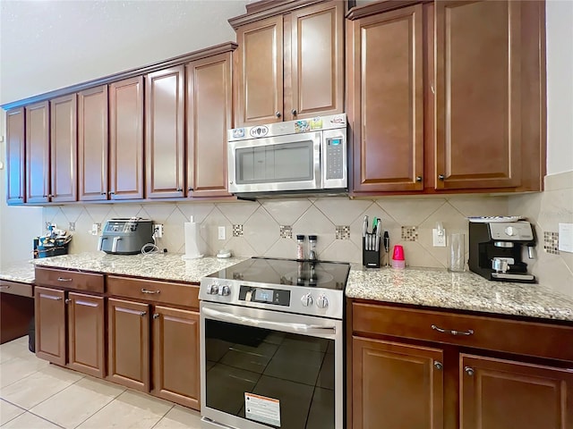 1027 Cedar Bay Ln, Winter Springs, FL 32708 - kitchen with appliances with stainless steel finishes, decorative backsplash, light stone countertops, and light tile patterned floors