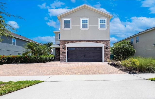 311 W Falls Dr, Kissimmee, FL 34747 - view of front of home with stone siding, decorative driveway, a garage, and stucco siding