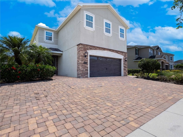 311 W Falls Dr, Kissimmee, FL 34747 - view of front of property featuring an attached garage, stone siding, stucco siding, and driveway