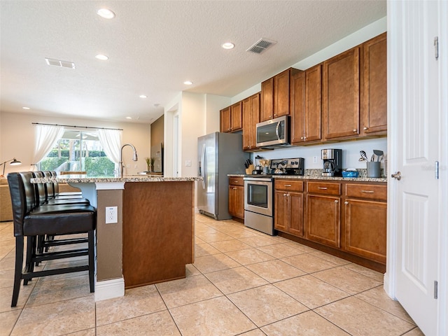 311 W Falls Dr, Kissimmee, FL 34747 - kitchen featuring stainless steel appliances, brown cabinets, light stone countertops, recessed lighting, and a textured ceiling
