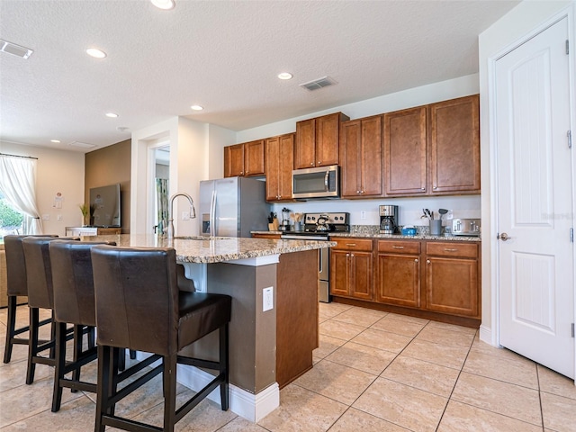 311 W Falls Dr, Kissimmee, FL 34747 - kitchen with stainless steel appliances, a textured ceiling, a breakfast bar, brown cabinetry, and recessed lighting
