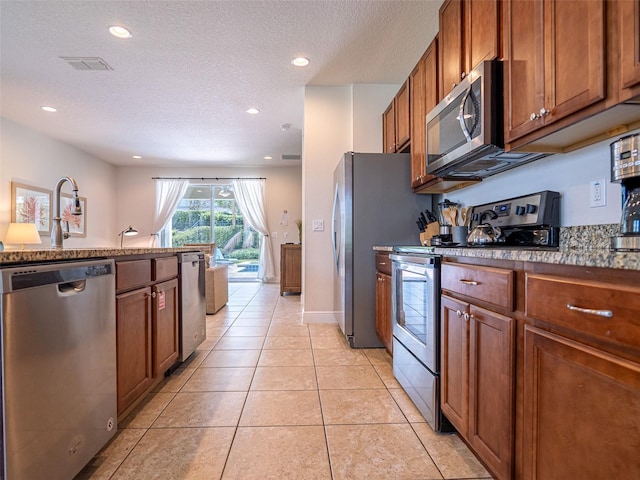 311 W Falls Dr, Kissimmee, FL 34747 - kitchen featuring appliances with stainless steel finishes, a textured ceiling, brown cabinetry, recessed lighting, and light tile patterned flooring