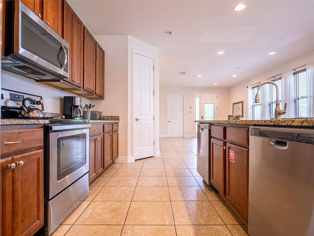 311 W Falls Dr, Kissimmee, FL 34747 - kitchen with appliances with stainless steel finishes, plenty of natural light, light tile patterned floors, brown cabinets, and recessed lighting