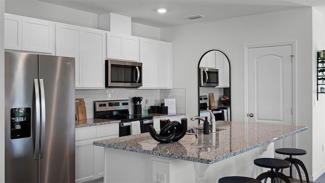 1566 Dalehurst Ln, Kissimmee, FL 34744 - kitchen with stainless steel appliances, a kitchen breakfast bar, decorative backsplash, and light stone countertops