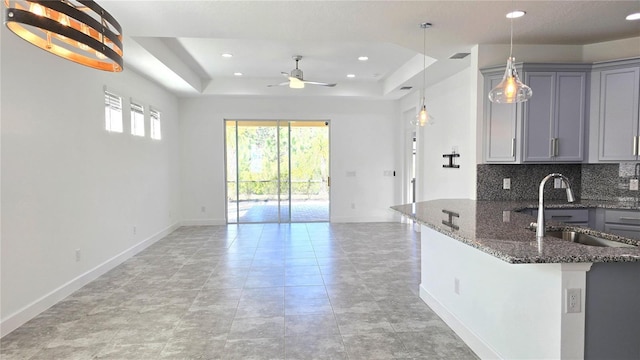 726 Coral Reef Way, Daytona Beach, FL 32124 - kitchen with gray cabinetry, a sink, a raised ceiling, open floor plan, and ceiling fan