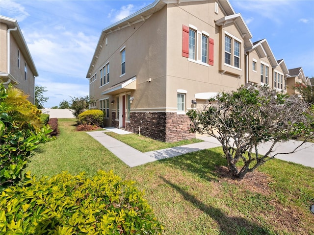 view of home's exterior with stucco siding, a lawn, a residential view, and stone siding