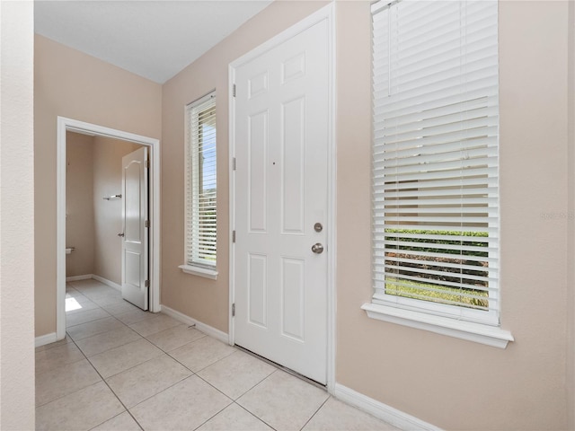 foyer entrance with light tile patterned floors and baseboards