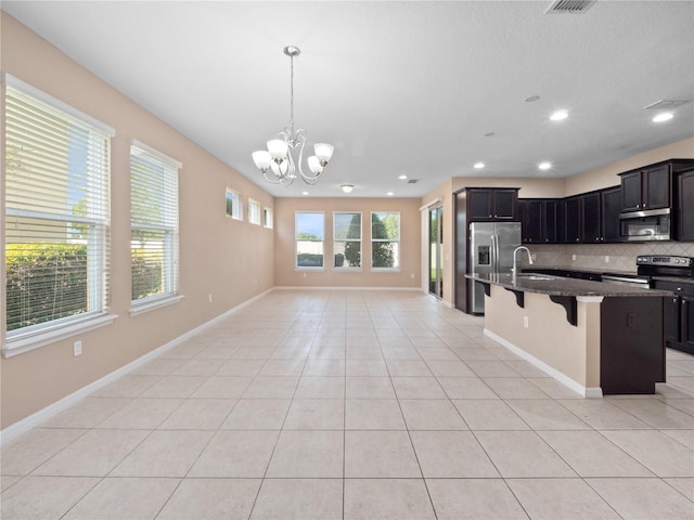 kitchen featuring stainless steel appliances, a chandelier, open floor plan, a kitchen bar, and tasteful backsplash