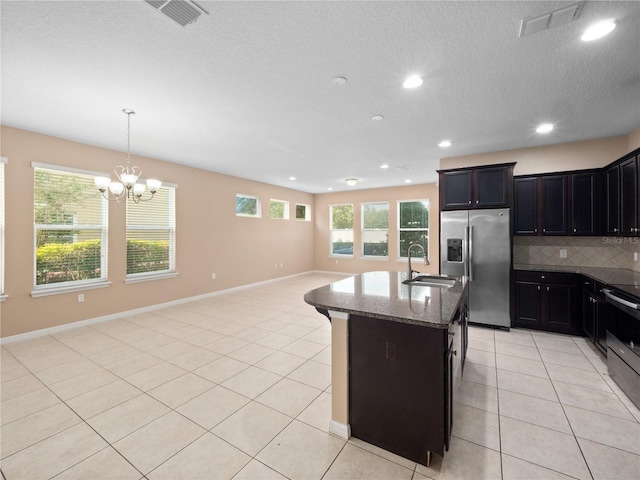 kitchen featuring stainless steel fridge with ice dispenser, a sink, dark stone countertops, open floor plan, and decorative backsplash