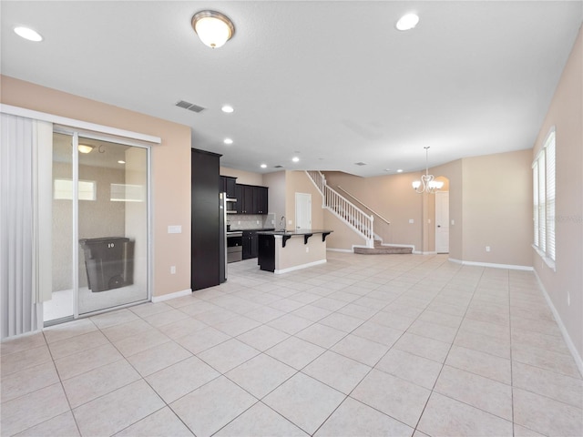 unfurnished living room featuring a chandelier, light tile patterned flooring, a sink, recessed lighting, and baseboards