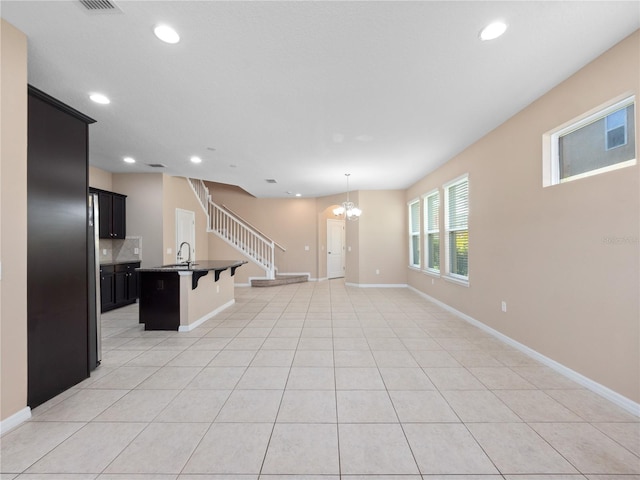 unfurnished living room featuring a chandelier, recessed lighting, light tile patterned flooring, and baseboards