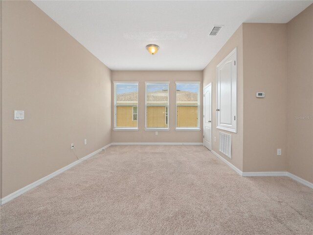 spare room featuring light carpet and baseboards