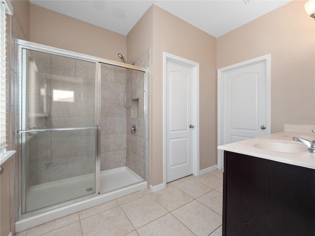 bathroom featuring tile patterned flooring, a shower stall, baseboards, and vanity