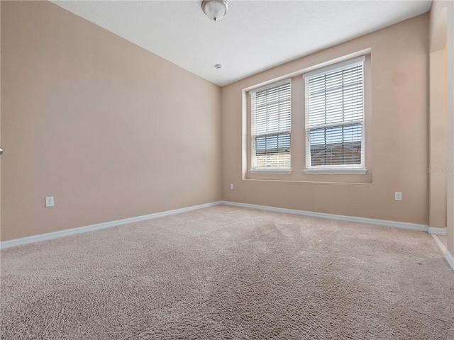 unfurnished room featuring baseboards and light carpet