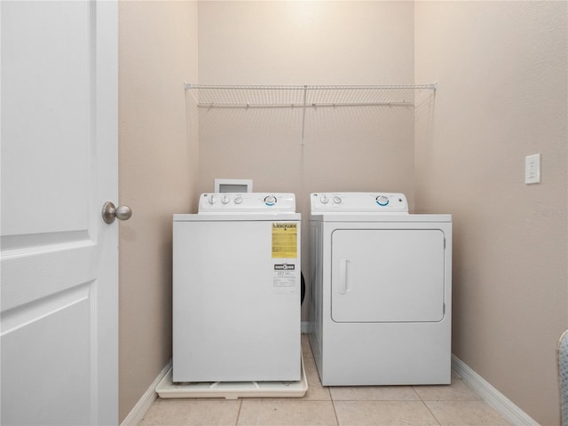laundry room featuring washing machine and dryer, light tile patterned floors, and baseboards