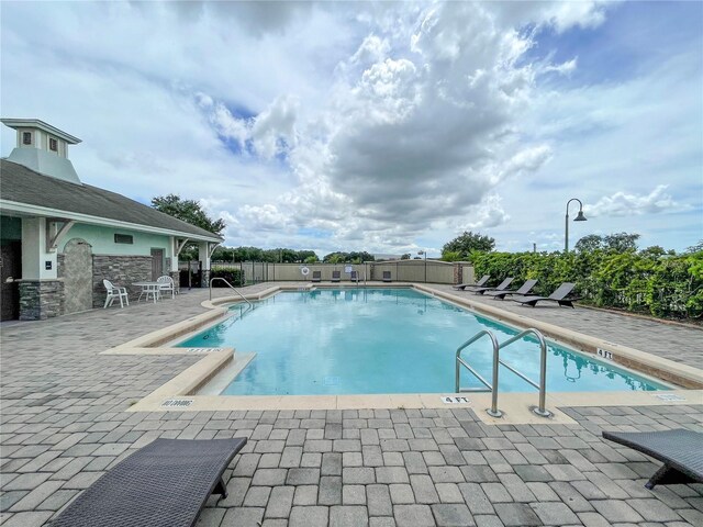community pool with a patio and fence