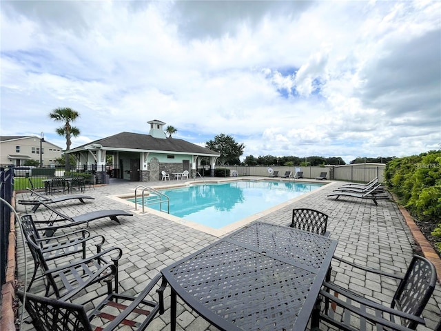 community pool with fence and a patio area